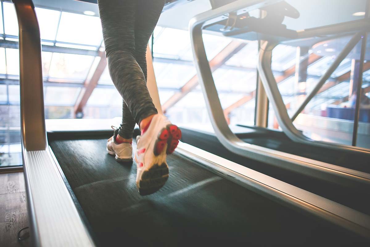 A person is walking on the treadmill in an indoor gym.